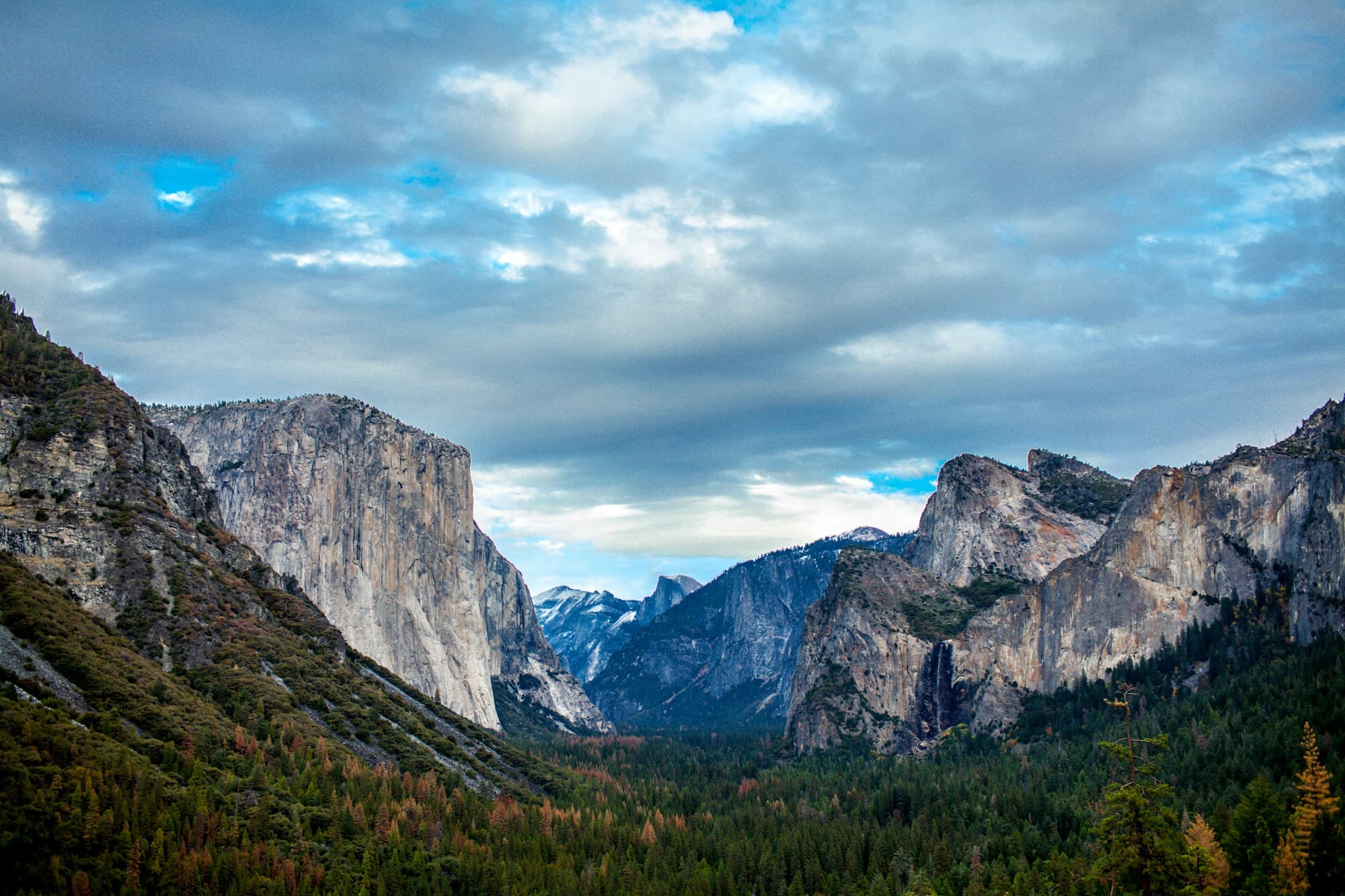 Acantilados de granito y bosques del valle de Yosemite bajo un cielo de nubes.